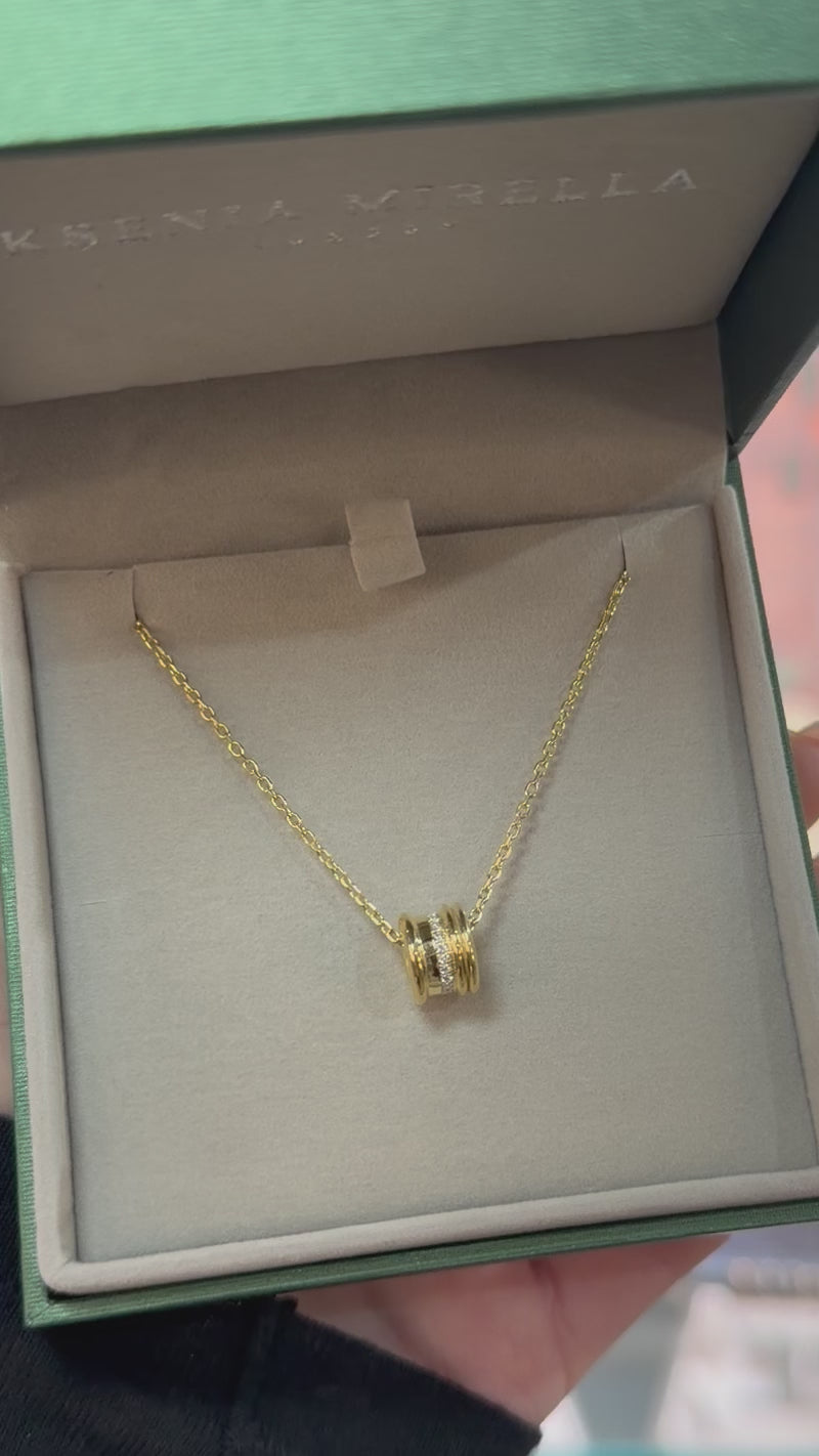 A video of a yellow gold white diamond small single bead rondel necklace in a branded box 