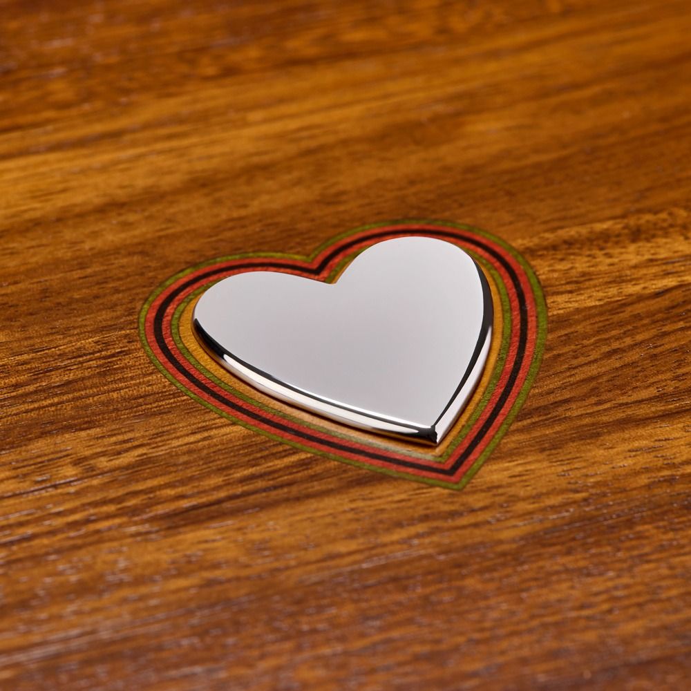 Heart-shaped metallic object on a wooden surface