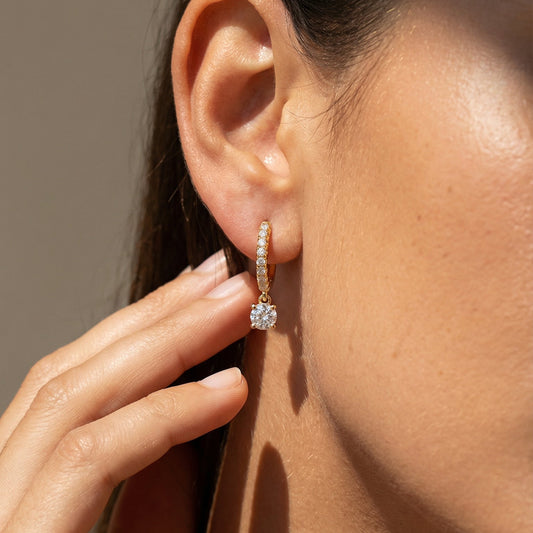 Close-up of a person wearing a diamond earring with a blurred background