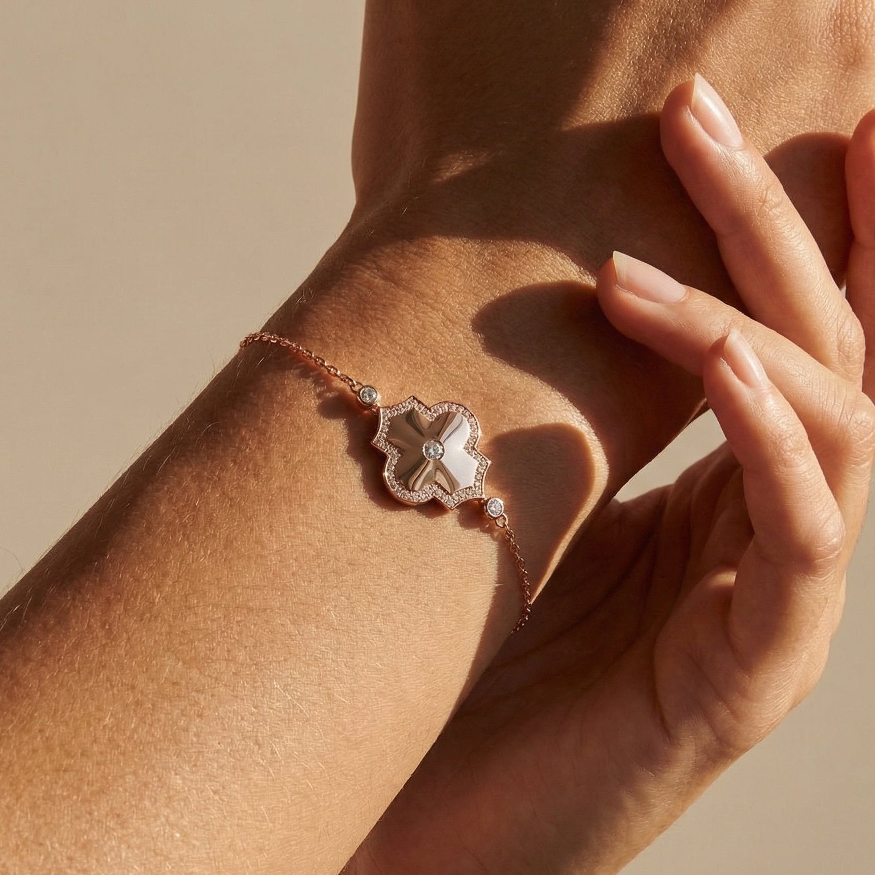 Close-up of a hand wearing a bracelet with a decorative clasp on a beige background
